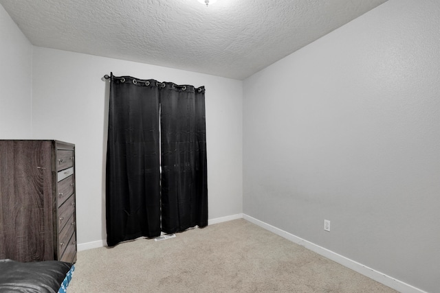 bedroom with light carpet, a textured ceiling, and baseboards