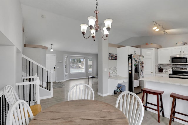 dining room with baseboards, stairs, vaulted ceiling, light wood-type flooring, and a chandelier