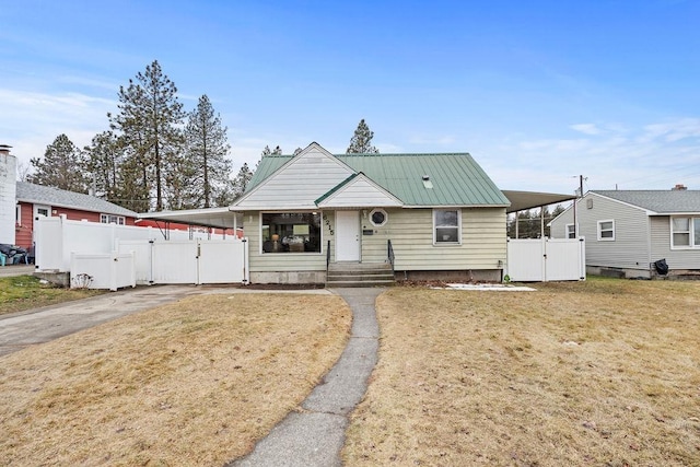 view of front of house with metal roof, fence, driveway, a gate, and a front yard