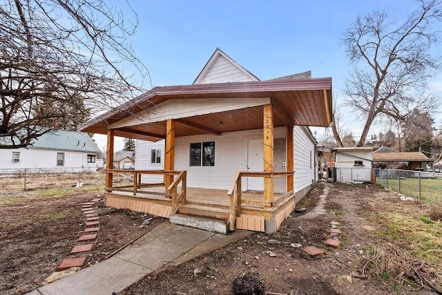 rear view of property with covered porch and fence