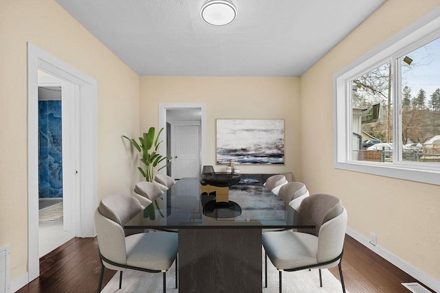 dining room featuring dark wood finished floors, visible vents, and baseboards