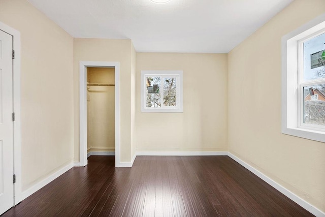 unfurnished bedroom featuring dark wood-style floors, a closet, and baseboards