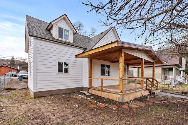 back of house featuring covered porch and roof with shingles