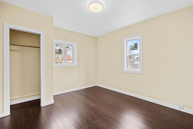 unfurnished bedroom featuring baseboards, dark wood finished floors, and a closet