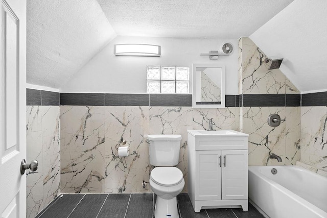 full bathroom with tile walls, toilet, vaulted ceiling, a textured ceiling, and vanity