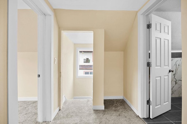 hallway featuring dark colored carpet and baseboards