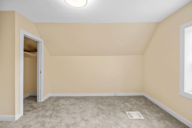 bonus room featuring lofted ceiling, carpet, visible vents, and baseboards