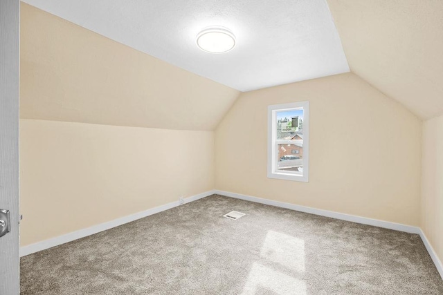 bonus room featuring lofted ceiling, carpet flooring, visible vents, and baseboards