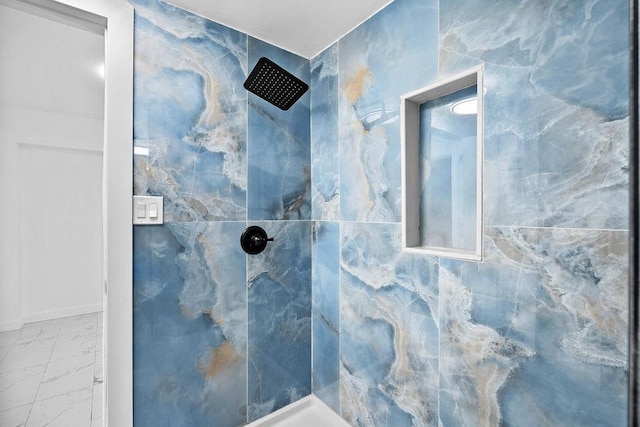 full bathroom with marble finish floor and a tile shower