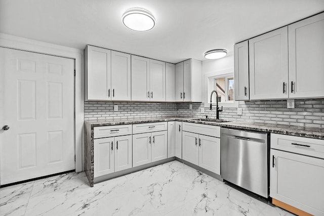 kitchen with a sink, marble finish floor, dark stone counters, and stainless steel dishwasher