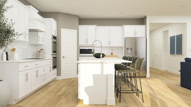 kitchen featuring light wood finished floors, a center island with sink, white cabinets, appliances with stainless steel finishes, and light countertops