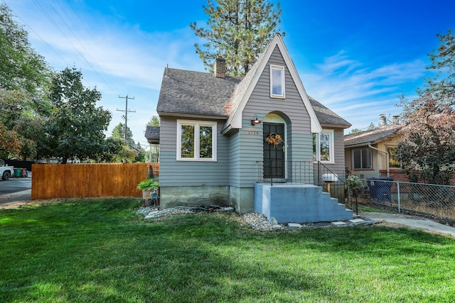 view of front of house with a shingled roof, a front yard, fence, and a chimney