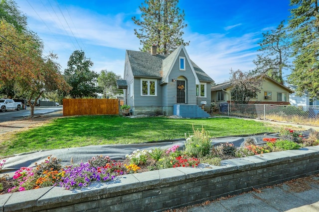 view of front of house featuring fence, a chimney, and a front lawn