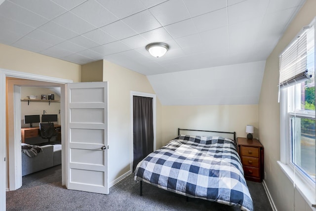 carpeted bedroom with lofted ceiling and baseboards