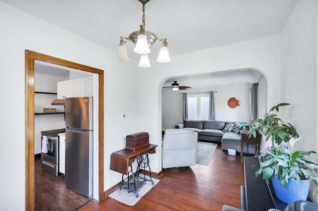 living room with arched walkways, ceiling fan with notable chandelier, dark wood finished floors, and baseboards