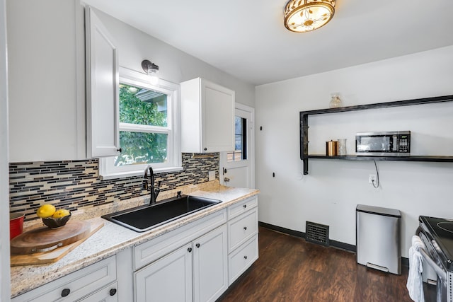 kitchen with stainless steel appliances, dark wood-type flooring, a sink, visible vents, and backsplash