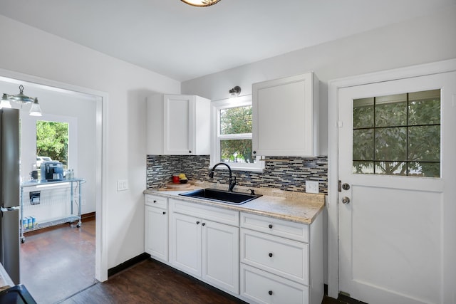 kitchen with tasteful backsplash, baseboards, white cabinets, dark wood-type flooring, and a sink