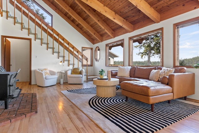 living area featuring beamed ceiling, wooden ceiling, a wood stove, and hardwood / wood-style flooring