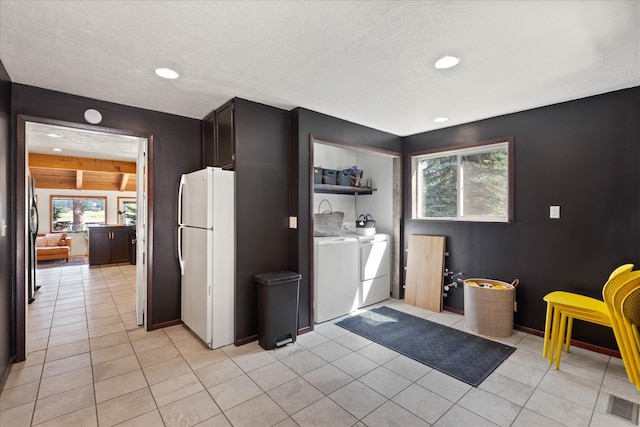 kitchen with freestanding refrigerator, light tile patterned floors, visible vents, and separate washer and dryer