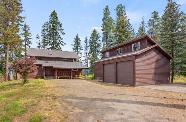 exterior space featuring an attached garage, dirt driveway, and metal roof