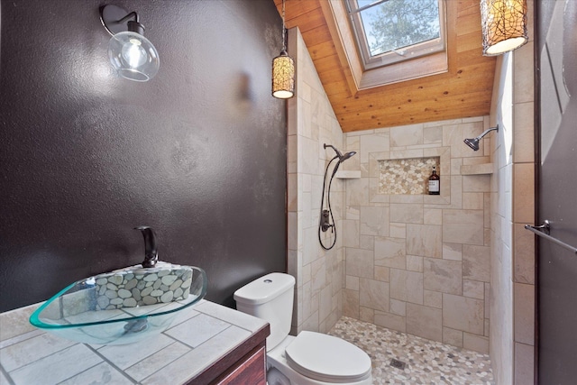 full bath with vaulted ceiling with skylight, a tile shower, and toilet