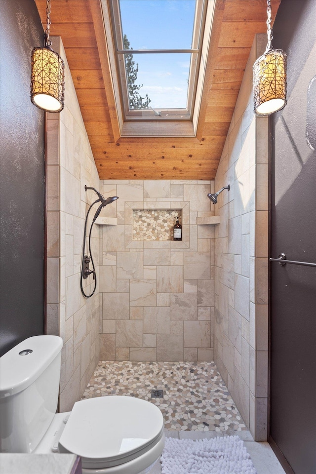 bathroom with lofted ceiling with skylight, a tile shower, and toilet