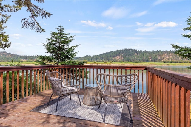 wooden deck with a water view and a forest view