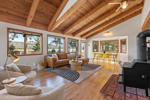 living room featuring wooden ceiling, wood finished floors, a ceiling fan, beam ceiling, and a wood stove