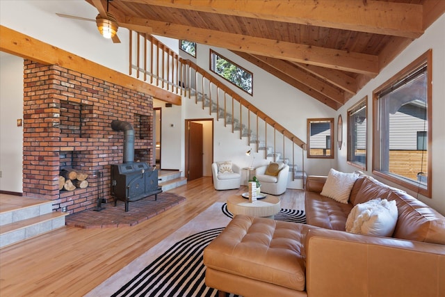 living room with wooden ceiling, stairway, wood finished floors, a wood stove, and vaulted ceiling with beams