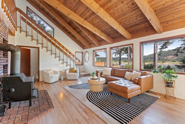 living area featuring a wood stove, wood finished floors, high vaulted ceiling, wooden ceiling, and beamed ceiling