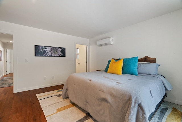 bedroom with baseboards, wood finished floors, and an AC wall unit