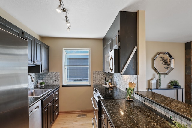 kitchen featuring visible vents, light wood-style flooring, appliances with stainless steel finishes, a sink, and backsplash