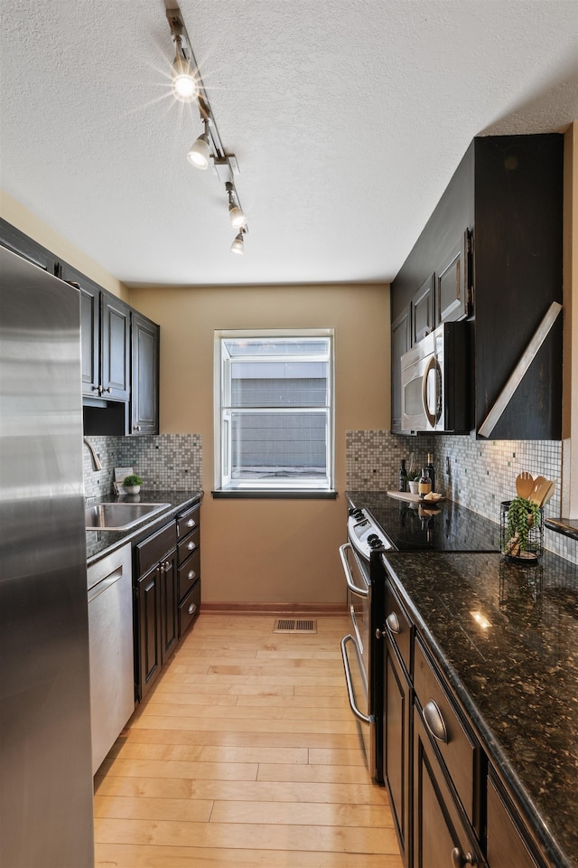 kitchen featuring light wood-style flooring, stainless steel appliances, a sink, visible vents, and tasteful backsplash