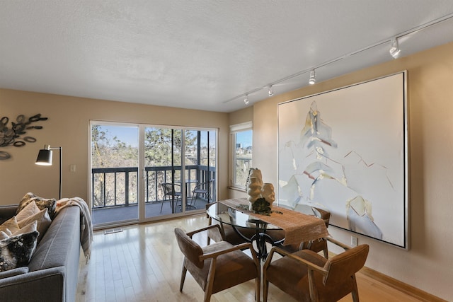 dining area featuring light wood-type flooring and a textured ceiling