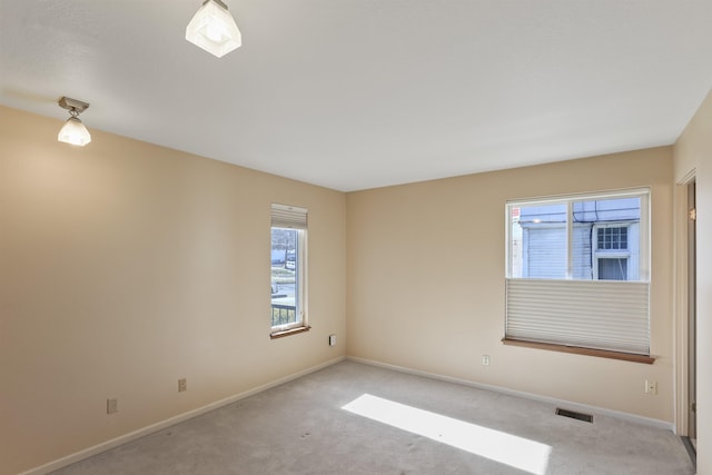 spare room featuring carpet floors, visible vents, and baseboards