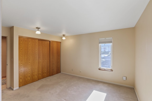 unfurnished bedroom with baseboards, a closet, and light colored carpet