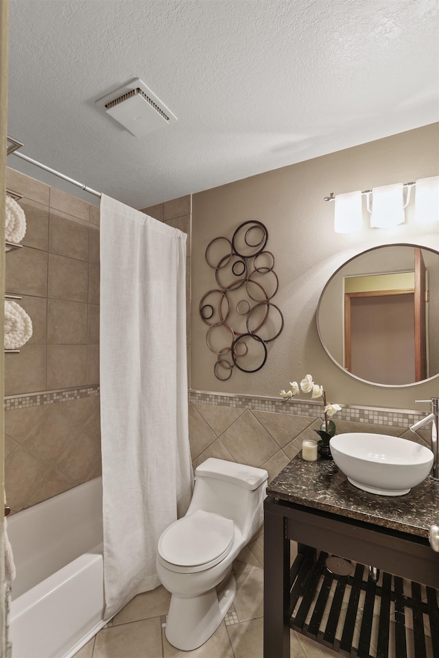 bathroom with visible vents, toilet, tile patterned floors, a textured ceiling, and tile walls