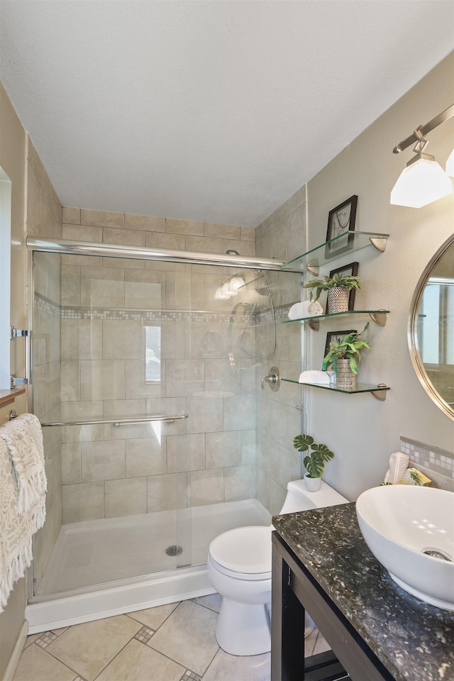 bathroom featuring vanity, a stall shower, tile patterned flooring, and toilet