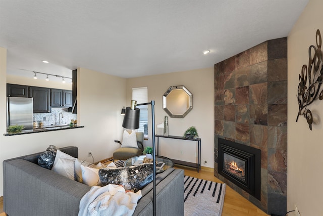 living room featuring light wood-type flooring and a tiled fireplace