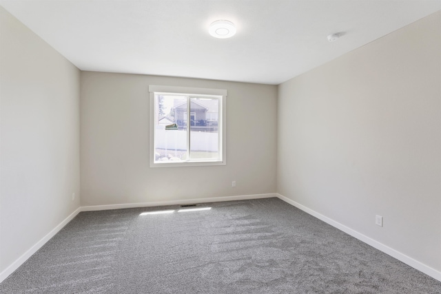 empty room featuring carpet and baseboards