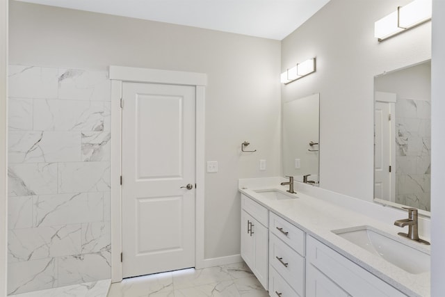 bathroom featuring marble finish floor, double vanity, a sink, and baseboards