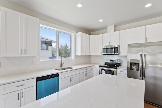 kitchen featuring stainless steel appliances, white cabinetry, a sink, and decorative backsplash