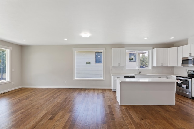 kitchen featuring baseboards, dark wood-type flooring, stainless steel appliances, light countertops, and a sink