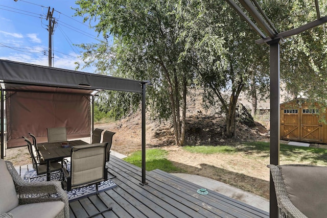 wooden deck with an outbuilding, a storage shed, and outdoor dining space