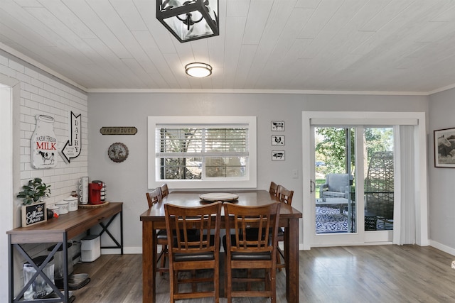 dining space with wooden ceiling, brick wall, wood finished floors, baseboards, and crown molding