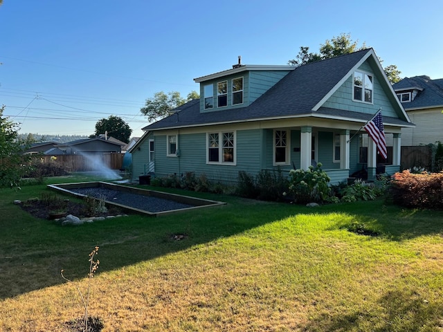 rear view of house with a shingled roof and a lawn