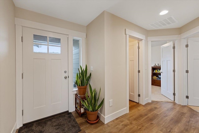 foyer entrance with light wood-style flooring, visible vents, and baseboards