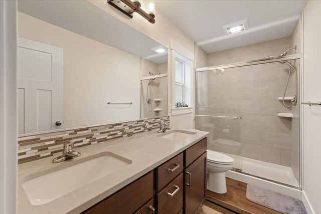 full bathroom with a stall shower, backsplash, and a sink