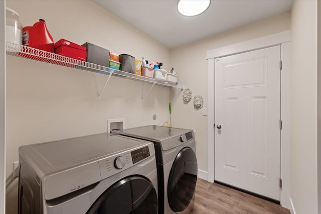 washroom with light wood-type flooring, laundry area, washing machine and dryer, and baseboards