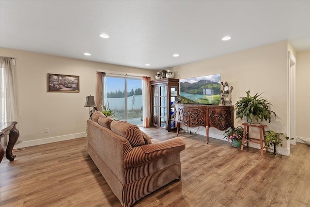 living room featuring baseboards, recessed lighting, and light wood-style floors